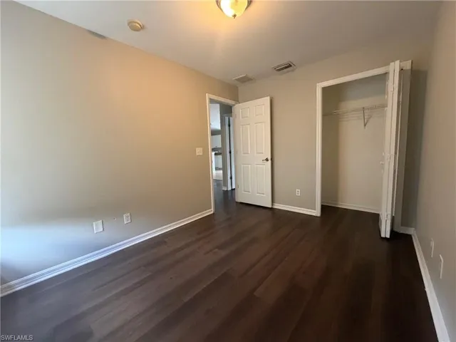 Unfurnished bedroom featuring dark wood finished floors and a closet