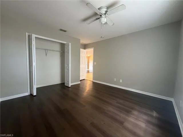 Unfurnished bedroom featuring a closet, ceiling fan, and dark wood-type flooring