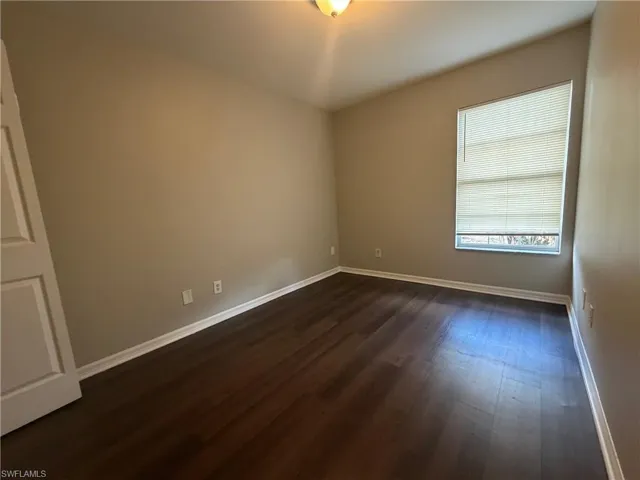 Spare room with baseboards and dark wood-style floors
