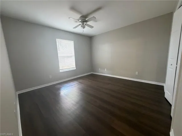 Unfurnished bedroom featuring a closet, dark wood finished floors, and ceiling fan