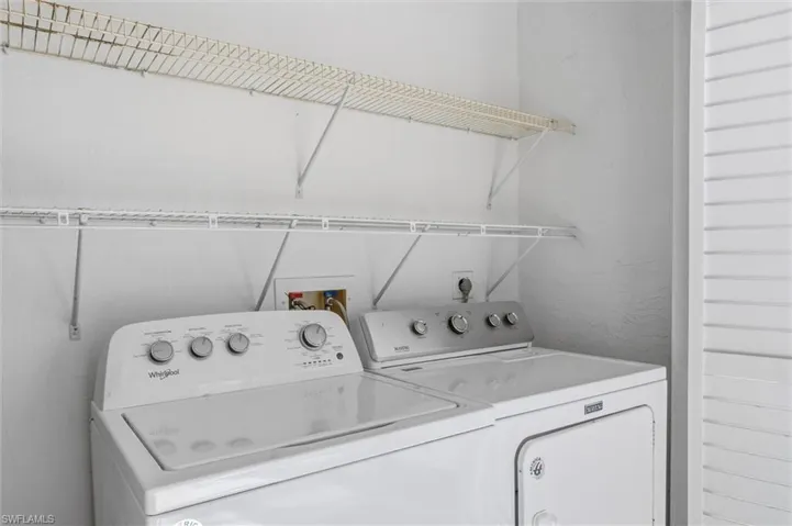 Washroom with washing machine and clothes dryer and a textured wall