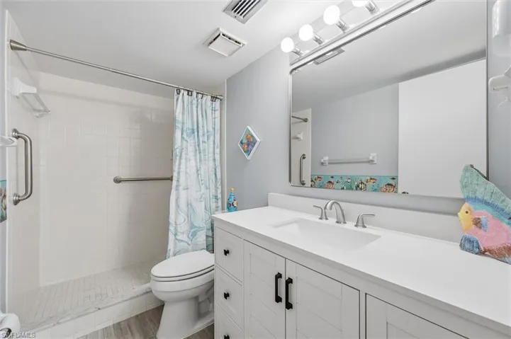 Full bathroom with vanity, a shower stall, and light wood finished floors