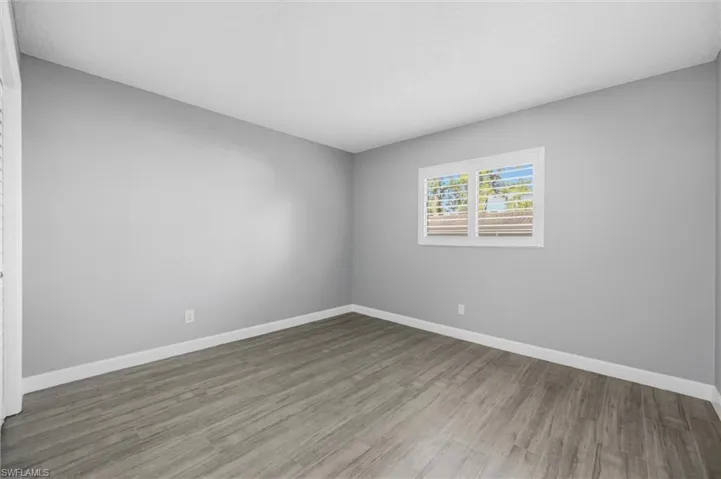 Unfurnished room with wood finished floors and baseboards