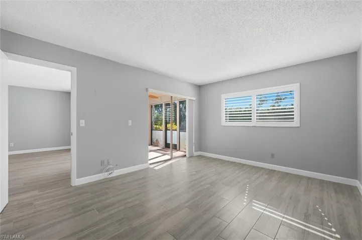 Empty room with a textured ceiling and light wood finished floors