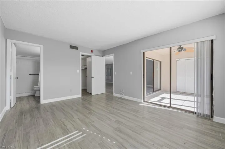 Unfurnished bedroom featuring a walk in closet, light wood-type flooring, connected bathroom, and access to outside