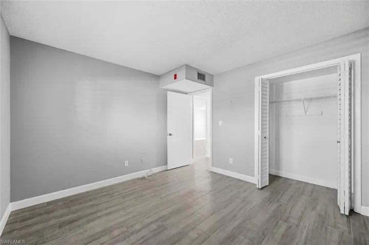 Unfurnished bedroom with wood finished floors, a textured ceiling, and a closet