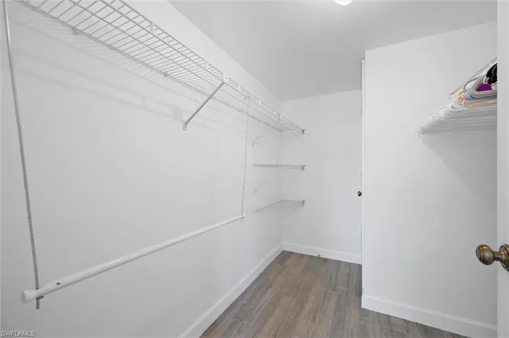 Walk in closet with dark wood finished floors