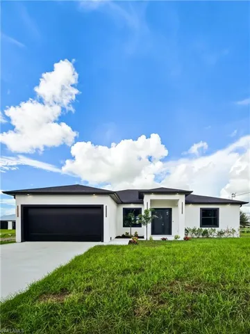 Prairie-style house with concrete driveway, a garage, stucco siding, and a front lawn