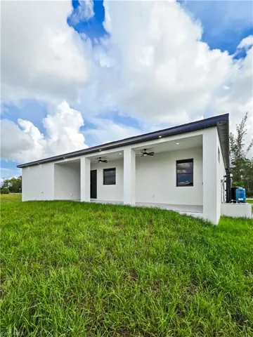 Back of house with a ceiling fan, stucco siding, a patio area, and a yard