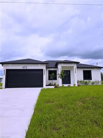 Prairie-style house with an attached garage, concrete driveway, a front lawn, and stucco siding