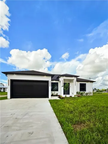 View of front of property with driveway, stucco siding, an attached garage, and a front yard