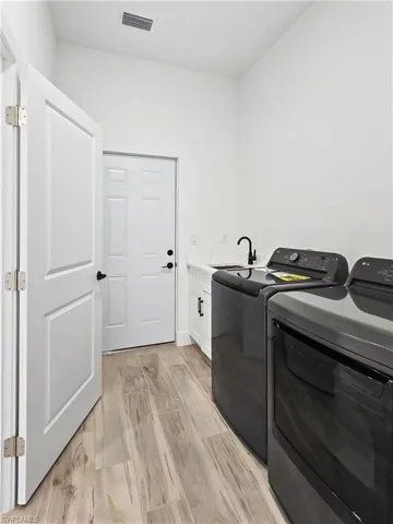 Laundry room featuring light wood-style flooring, washer and clothes dryer, and cabinet space