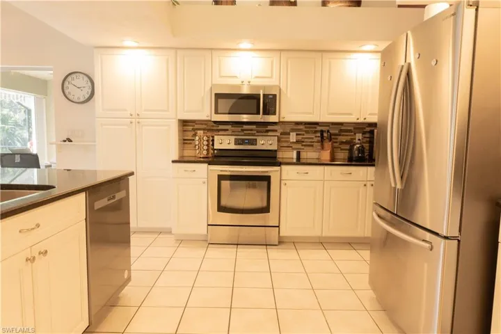 Kitchen with white cabinetry, appliances with stainless steel finishes, decorative backsplash, and light tile patterned floors