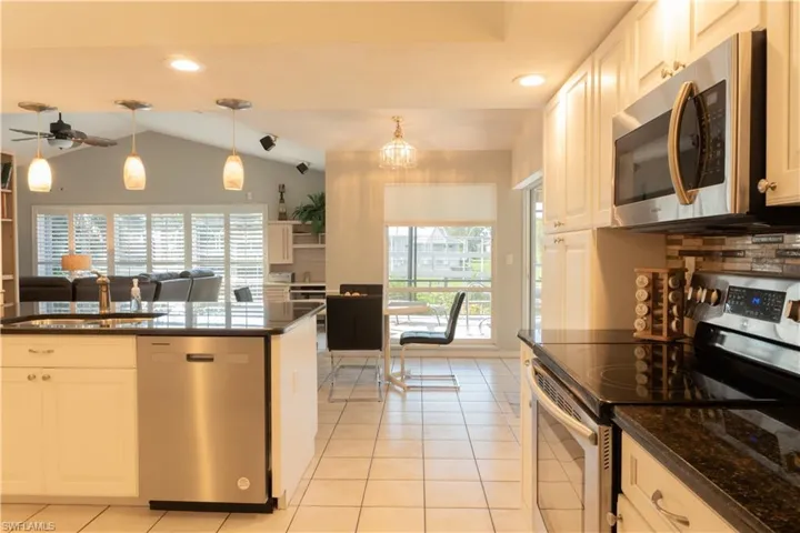 Kitchen with white cabinetry, appliances with stainless steel finishes, pendant lighting, and light tile patterned floors