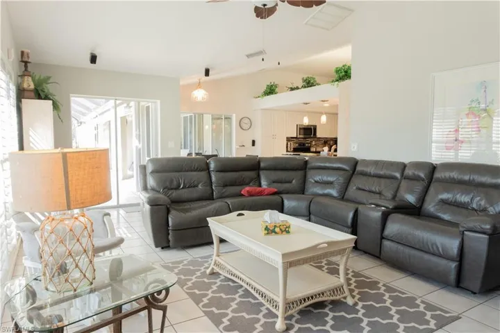 Tiled living room featuring lofted ceiling and ceiling fan