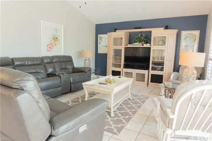 Living room featuring light tile patterned flooring and vaulted ceiling