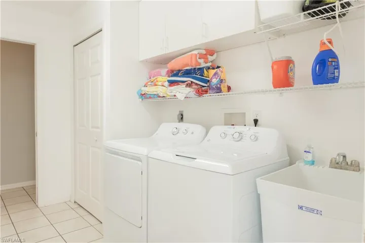 Washroom featuring cabinets, light tile patterned flooring, sink, and independent washer and dryer