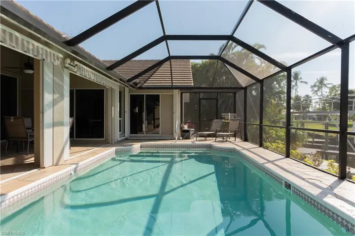 View of pool with a patio area and glass enclosure