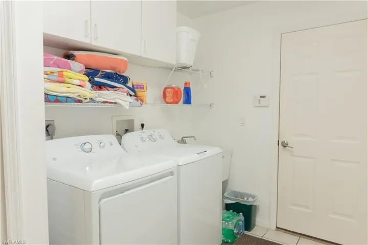 Laundry room with washer and clothes dryer, cabinets, and light tile patterned flooring