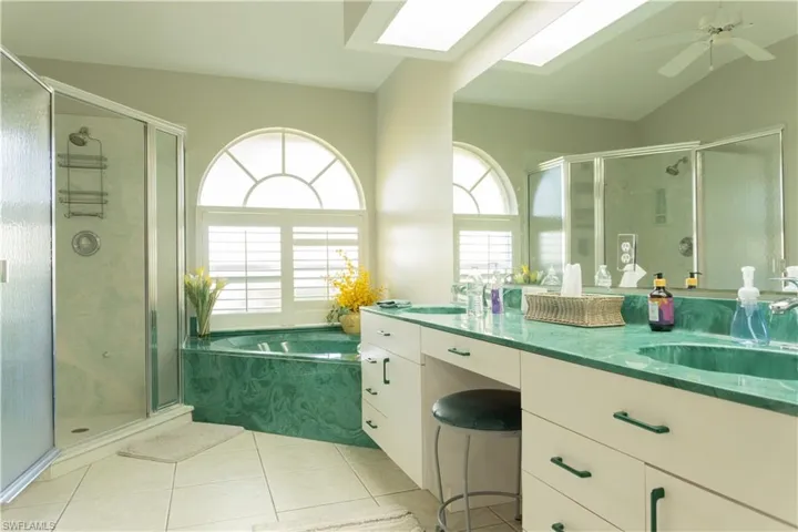 Bathroom with vanity, lofted ceiling with skylight, tile patterned floors, and independent shower and bath