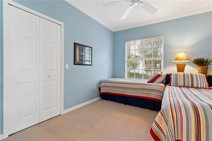 Carpeted bedroom featuring a closet, ceiling fan, and ornamental molding