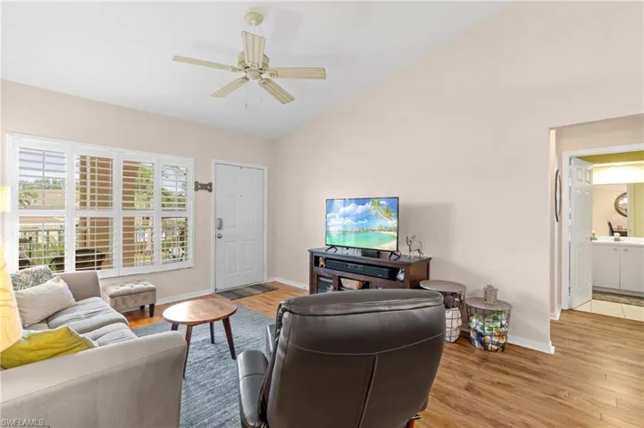 Living room featuring ceiling fan, light wood-type flooring, and vaulted ceiling