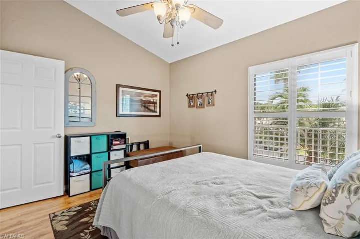 Bedroom with multiple windows, light hardwood / wood-style floors, ceiling fan, and lofted ceiling