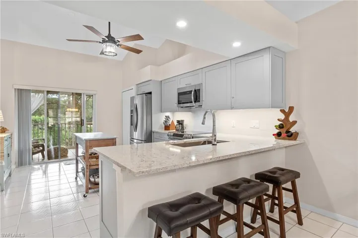 Kitchen with light stone counters, sink, kitchen peninsula, and stainless steel appliances
