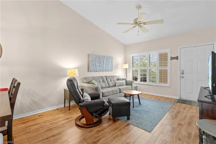 Living room with ceiling fan, high vaulted ceiling, and light hardwood / wood-style floors