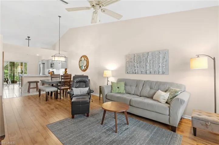 Living room with ceiling fan, vaulted ceiling, and hardwood / wood-style flooring
