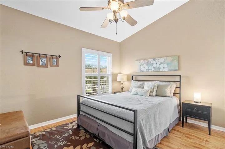 Bedroom with ceiling fan, light hardwood / wood-style floors, and vaulted ceiling