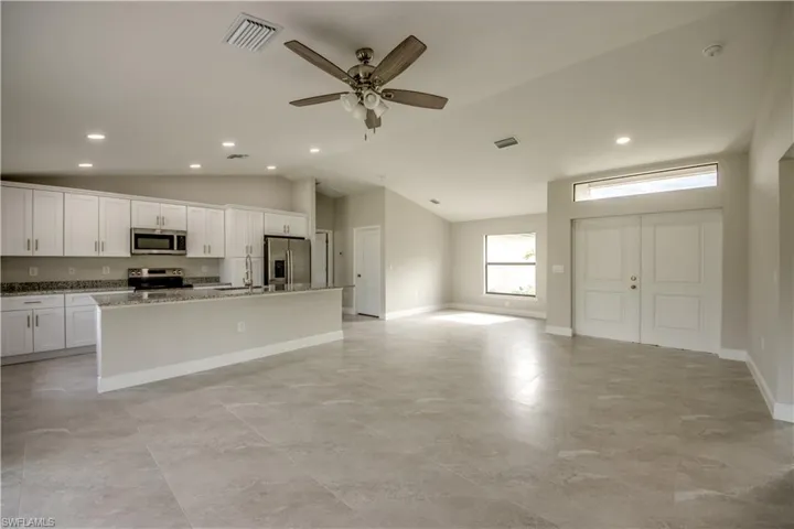 Kitchen featuring appliances with stainless steel finishes, vaulted ceiling, a kitchen island with sink, recessed lighting, and a ceiling fan