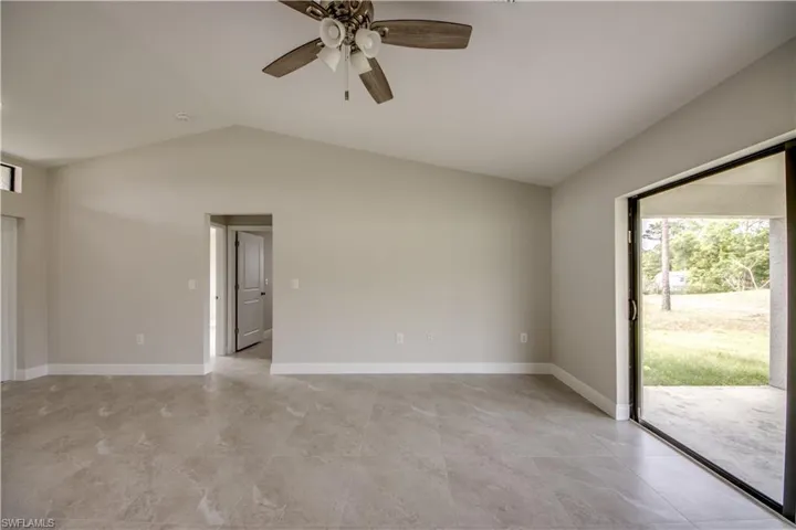 Empty room featuring lofted ceiling, ceiling fan, and light tile patterned floors