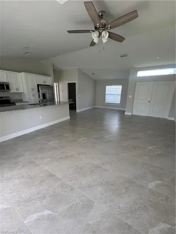 Unfurnished living room featuring ceiling fan and vaulted ceiling