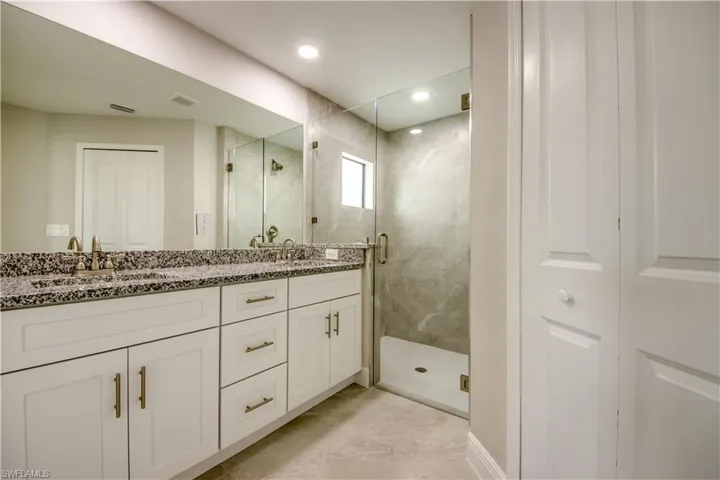 Bathroom with a marble finish shower and double vanity