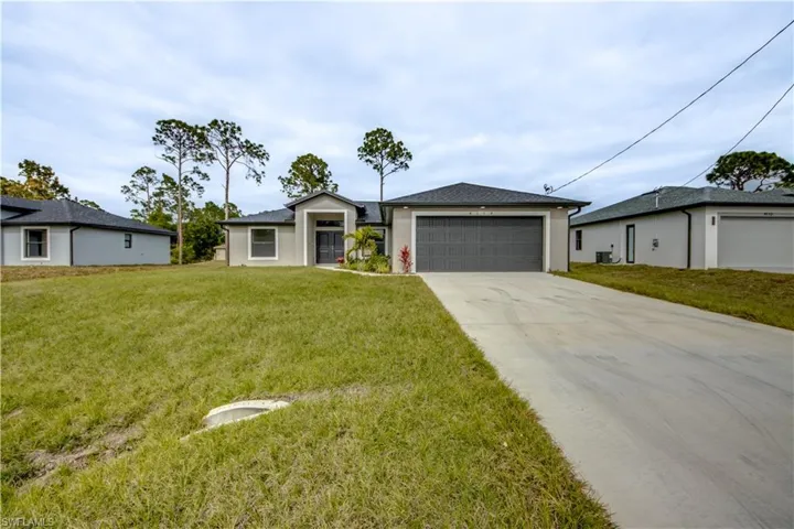 View of front of home with concrete driveway, a front lawn, an attached garage, and stucco siding