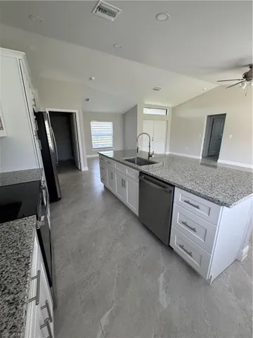 Kitchen with dishwasher, white cabinetry, vaulted ceiling, ceiling fan, and a spacious island