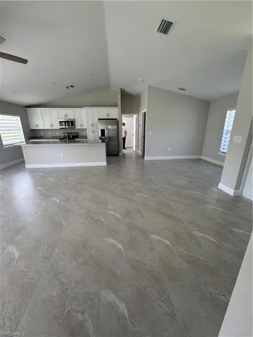 Unfurnished living room featuring vaulted ceiling and a ceiling fan