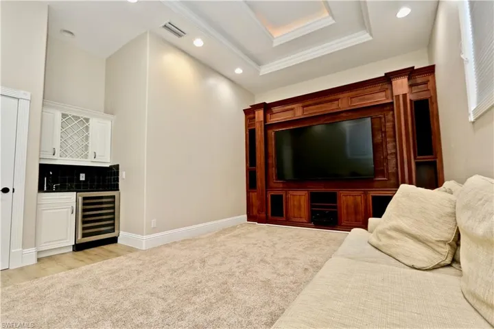 Living room featuring wine cooler, recessed lighting, light colored carpet, wet bar, and a raised ceiling