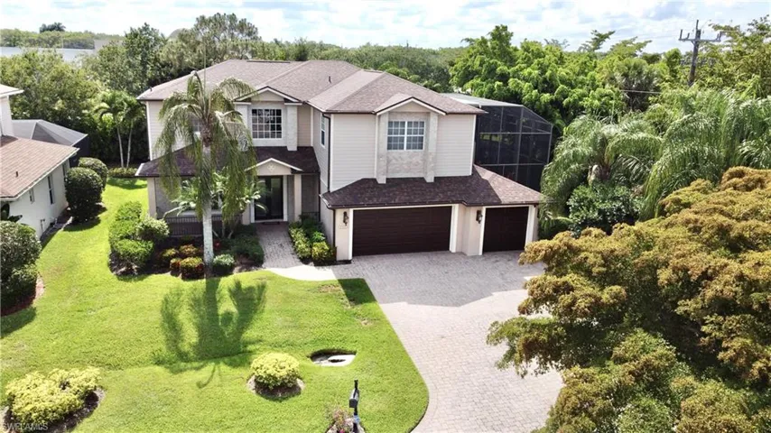 View of front of property featuring roof with shingles, decorative driveway, a garage, view of scattered trees, and a front yard
