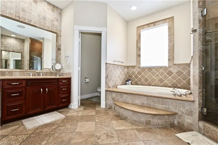 Bathroom with vanity, a bath, a shower stall, stone tile flooring, and recessed lighting