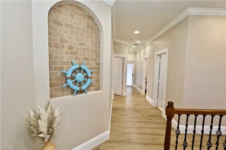 Corridor featuring crown molding, light wood-style floors, recessed lighting, and arched walkways