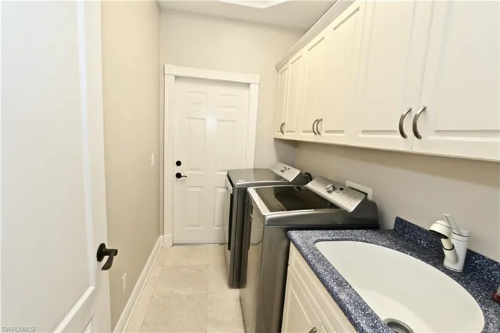 Laundry area featuring washer and clothes dryer, cabinet space, and light tile patterned flooring