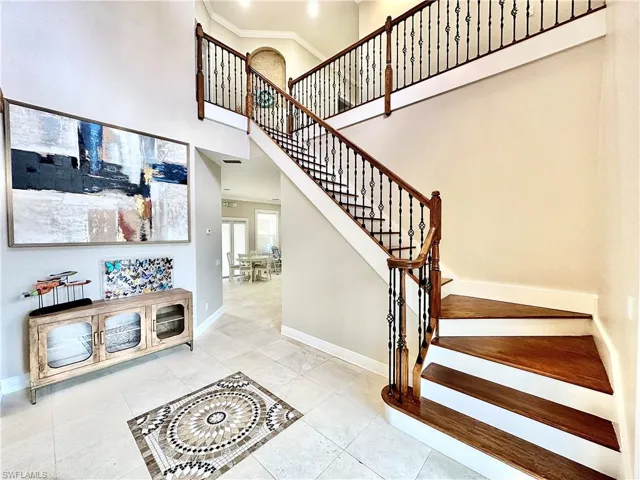 Stairway featuring a high ceiling, crown molding, and tile patterned flooring
