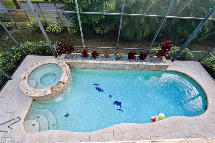 Relaxing pool / spa featuring glass enclosure and a patio