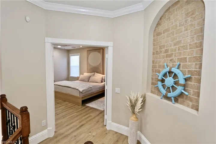 Bedroom featuring light wood finished floors, ornamental molding, and arched walkways