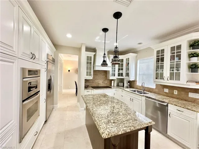 Kitchen featuring white cabinets, glass fronted cabinets, stainless steel appliances, decorative light fixtures, and open shelves