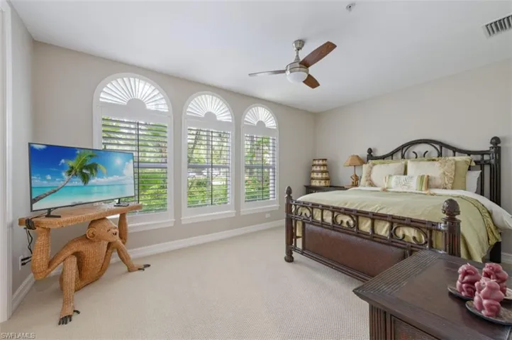 Carpeted bedroom with multiple windows and ceiling fan