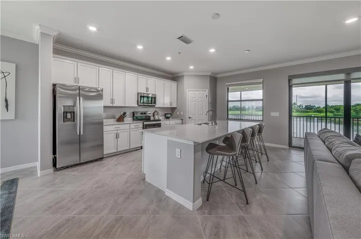 Kitchen featuring appliances with stainless steel finishes, sink, a breakfast bar area, white cabinets, and a center island with sink
