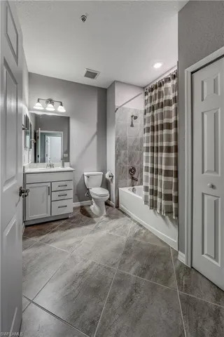 Full bathroom with shower / tub combo with curtain, tile patterned floors, toilet, a textured ceiling, and vanity